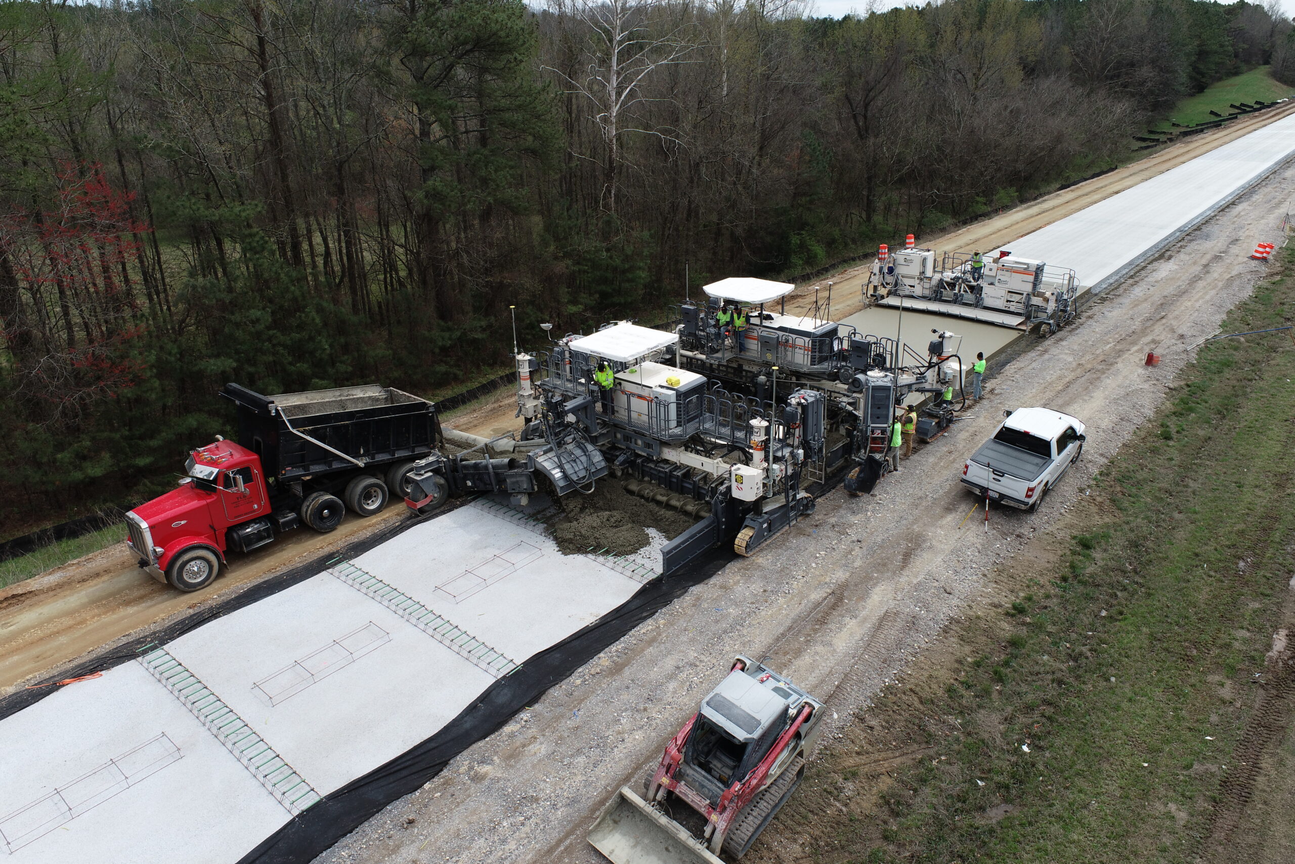 The machine uses internal vibrators for compaction and a mold to shape the pavement as it advances, ensuring a smooth, consistent surface ideal for large-scale infrastructure projects.